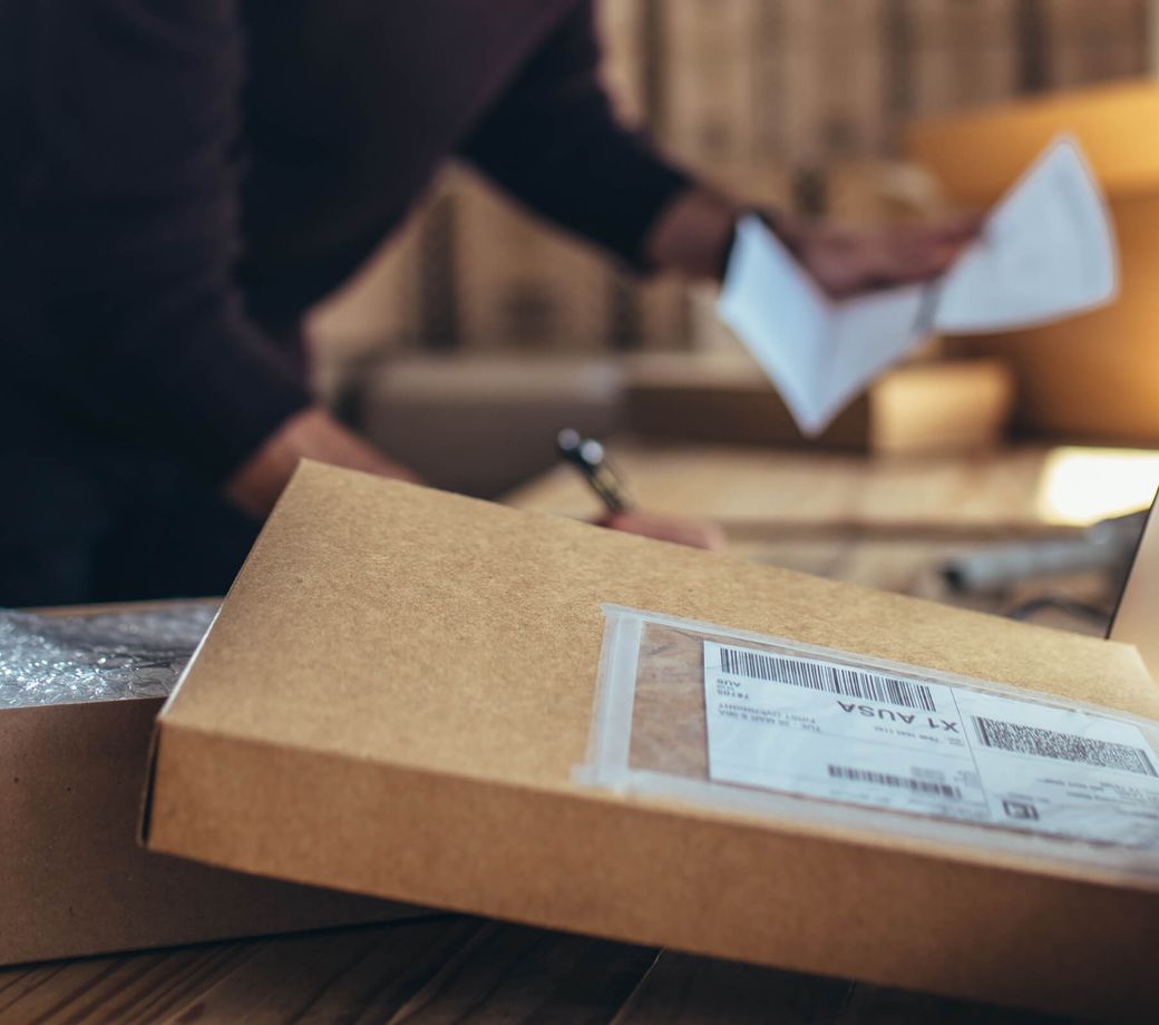 A labelled parcel at a packing station, an operator working in the background