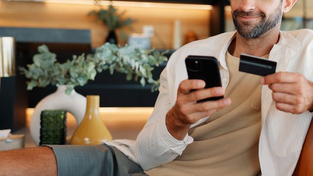A customer paying for an online purchase from a phone, bank card in hand