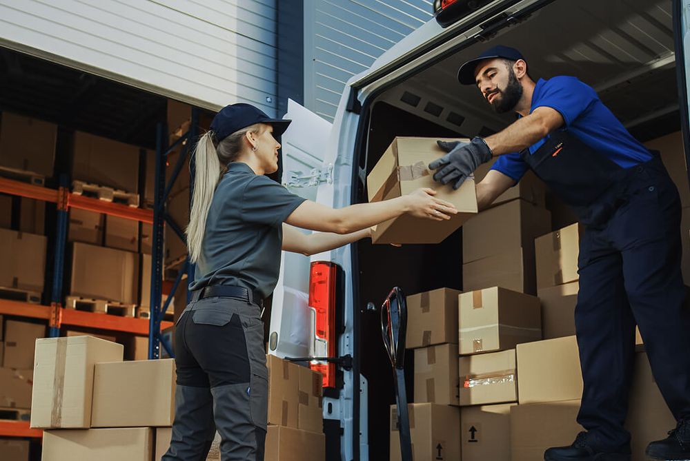 A parcel handed over on a loading dock, between the warehouse and a delivery van being loaded